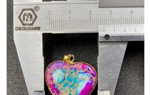 Macro shot of colorful imperial stone heart pendant measuring 26mm with gold-plated edge