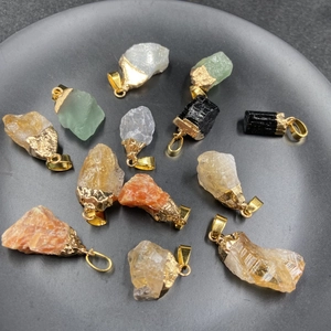 Colgantes de piedra natural en bruto con bordes dorados en bandeja de exhibición negra