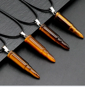 Macro shot of tiger eye bullet pendants on black rock with sleek metallic finish