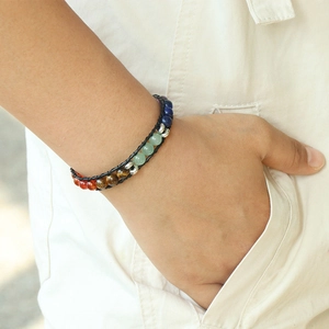 Bracelet perles en pierres naturelles sept chakras tissé en cuir sur le poignet d'un modèle