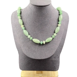 Détail d'un collier en pierres naturelles vertes sur un buste de mannequin gris