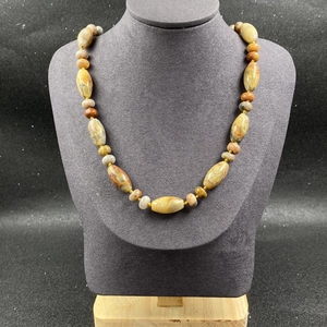 Détail d'un collier en pierres naturelles colorées sur un buste d'exposition gris