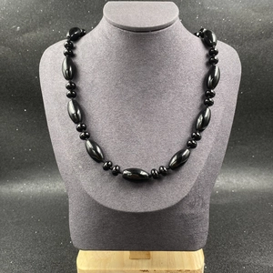 Détail d'un collier en pierre naturelle noire avec des perles d'olive polies sur support