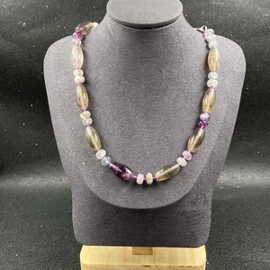 Détail de perles en fluorine naturelle violette et verte sur cordon tressé violet