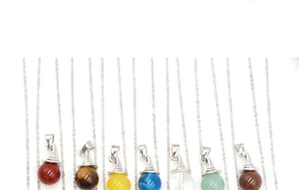 Multiple colorful natural gemstone sphere pendants with silver witch hat caps on chains