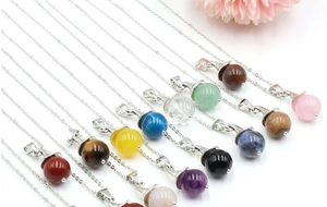 Detail of colorful crystal witch hat pendants featuring natural tiger eye and rose quartz