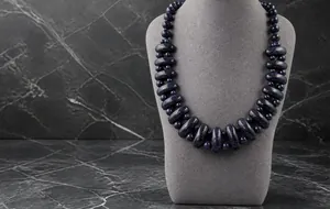 Detailed view of blue sand stone beaded necklace with oval tube beads on mannequin