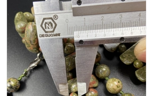 Vue macro mesurant l'épaisseur de 8 mm des perles de pierre d'unakite naturelle