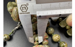 Vue macro mesurant des perles en unakite naturelle de 10mm avec un étrier