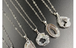 Detailed view of natural druzy agate necklaces with silver plating on a black background