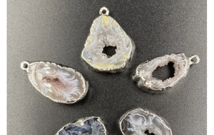Macro detail of natural druzy agate geode pendants with silver electroplated edges