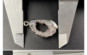 Macro shot showing the width measurement of a natural druzy agate pendant with silver edging