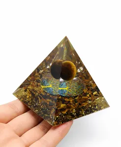 Detailed view of Orgone pyramid with tiger eye stones and tree of life symbol held in hand