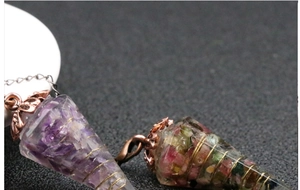 Detail of resin pendulum with amethyst chips, gold wire wrap and vintage bird clasp