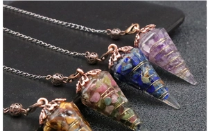 Macro detail of hexagonal resin crystal pendulums with embedded stones and gold wire wrap