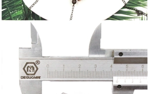 Measuring spiritual hollow ball pendant size with calipers showing 45mm dimension