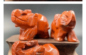 Detailopname van drie rode stenen olifantenbeelden op elegante houten voetstukken