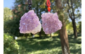 Dettaglio di ciondoli in ammasso di ametista grezza con cristalli viola naturali su cordoncini