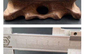 Detailweergave van de donkerbruine houten voet met nerf en meting met een schuifmaat