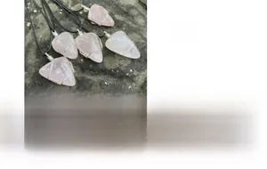 Détail macro du pendentif en quartz rose brut serti de fil sur cordon noir tissé