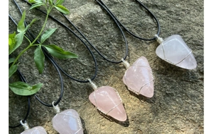 Détail de pierres de quartz rose irrégulières avec fil argenté sur cordons noirs