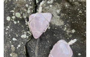 Vue détaillée de pendentifs en quartz rose brut sertis de fil métallique sur pierre naturelle