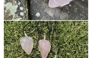 Détail d'un collier en quartz rose fait main avec fil enroulé sur pierre et herbe