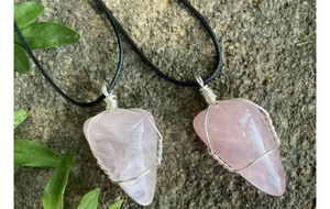 Détail de pendentifs en quartz rose avec enroulement de fil sur fond de roche naturelle