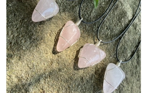 Détail d'un pendentif en quartz rose fait main avec fil enroulé sur roche naturelle