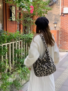 Detailed texture of leopard print plush tote bag shown in a cozy outdoor lifestyle setting