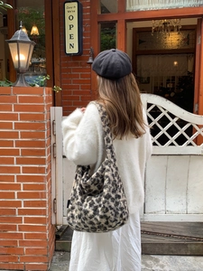 Outdoor street style shot of large leopard print plush tote bag paired with white sweater