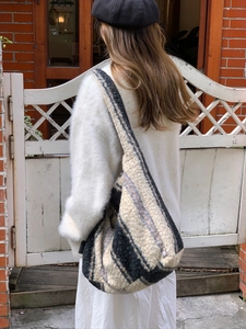 Detailed view of striped plush tote bag in fluffy fleece material worn on shoulder