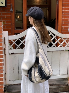 Outdoor shot of a large striped faux fur tote bag with soft knitted texture on shoulder