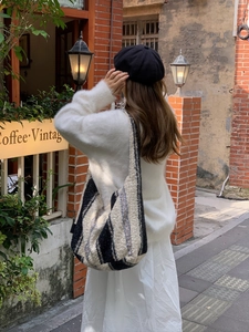 Detail of a large plush tote bag with navy and cream stripes in a vintage outdoor setting