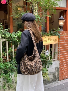Fuzzy leopard print hobo bag worn by model in a vintage cafe street setting