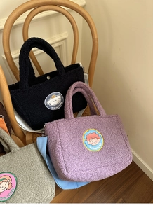 Cute lamb wool tote bags in black purple and grey with cartoon embroidery on a chair