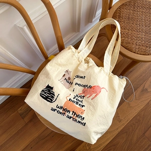 Nahaufnahme der cremefarbenen Kordelzug-Tasche mit niedlichen Katzen-Illustrationen
