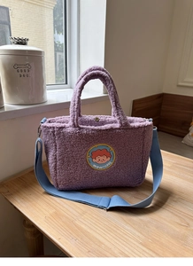 Detail of purple faux shearling tote bag with blue strap and magnetic metal closure