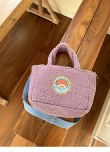 Detail of purple lamb wool tote bag with cartoon patch and adjustable blue shoulder strap