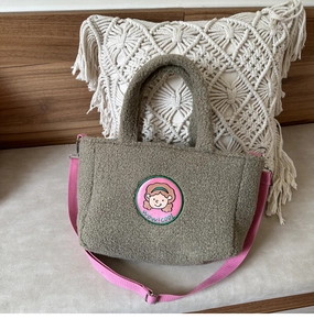 Detail of green sherpa tote bag with cartoon patch embroidery and pink shoulder strap