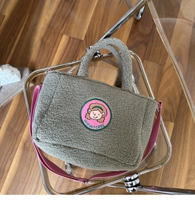 Detail of grey fleece tote bag with cartoon patch and pink adjustable canvas strap