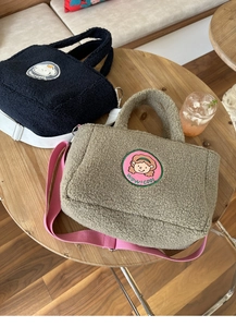 Detail of soft sherpa tote bags with 'wow! cool' patch and adjustable wide fabric straps