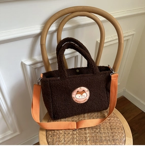 Detail of plush brown fleece tote bag with orange strap and cute cartoon fox patch