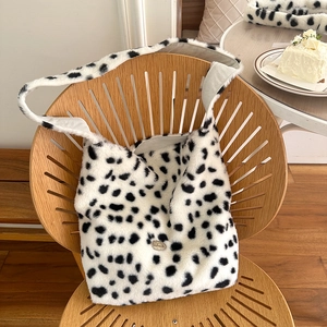 Fuffy cow print plush tote bag with handmade metal plate shown on a wooden chair