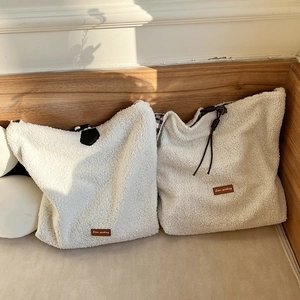 Detail of plush cream fleece tote bags with leather labels and check lining in cozy setting