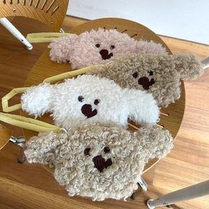 Detailed close-up of four colorful plush teddy bear purses on a wooden chair