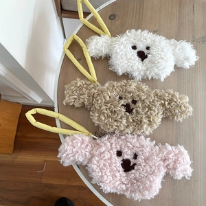 Close-up of curly plush dog coin purses in white, beige, and pink with yellow handles