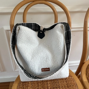 Detail of plush lamb fleece tote bag with classic checkered lining and horn button buckle