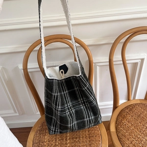 Close-up of black and white checkered plush tote bag with faux shearling lining on a chair