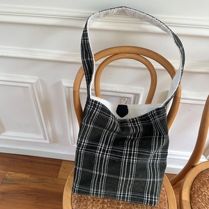 Detail of plush black and white checkered tote bag with white fleece lining on a chair